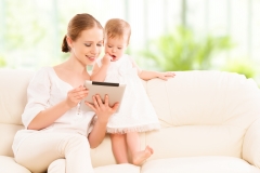 Mother And Baby Child With Tablet Computer On The Couch At Home