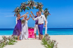 bride, groom and guests enjoying beach wedding in tropics, on wedding arch, setup background