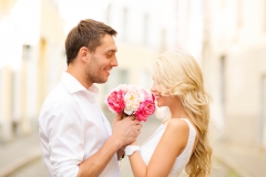 summer holidays, love, relationship and dating concept - couple with bouquet of flowers in the city